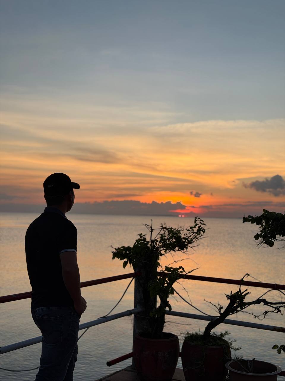 Puth Neng looking toward a sunset over the sea